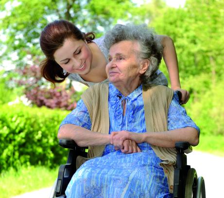 Persoon helpt bejaarde met rolstoel