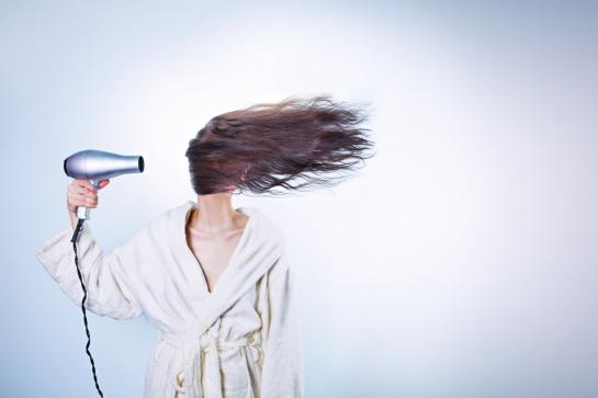 Vrouw blaast haar opzij met haardroger